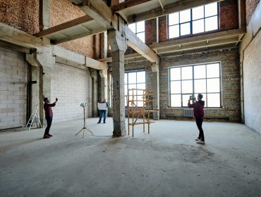 Two young contractors photographing unfinished structure inside building Two young contractors photographing unfinished structure inside building while their colleague looking at sketch on blueprint